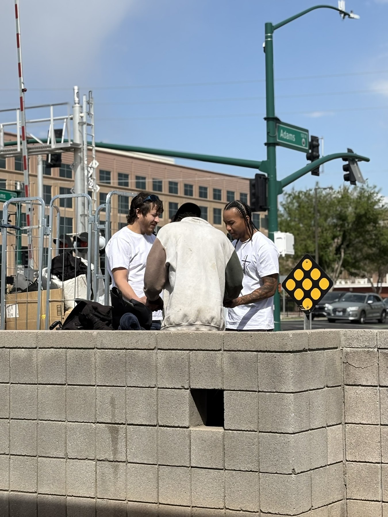 Two 4TK volunteers praying with a man on a downtown street corner