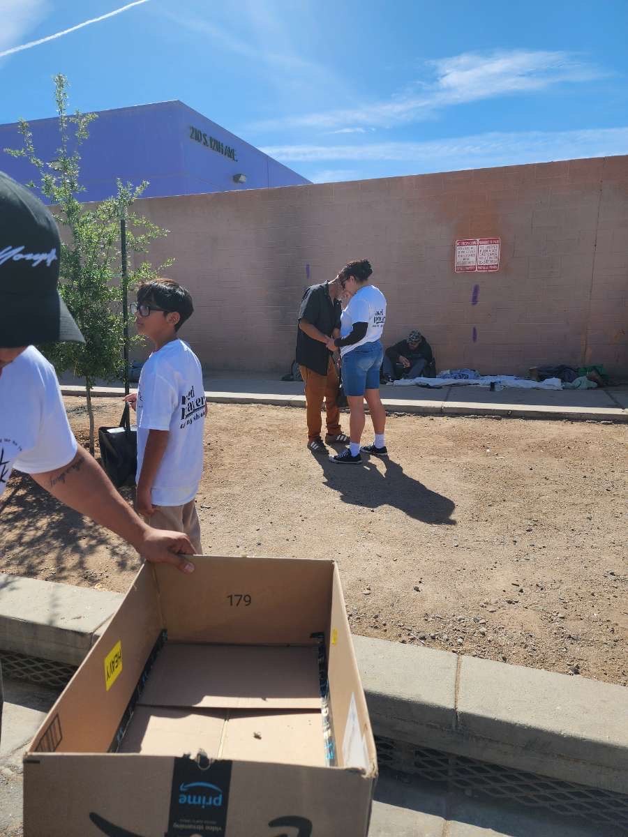 4TK volunteers carrying supply boxes while praying with someone on the street